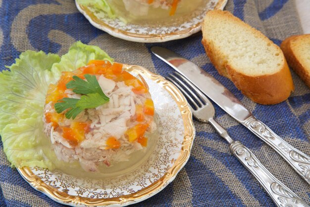 Foto geliertes hähnchenhackfleisch mit karotten, petersilie, knoblauchzehen und pfeffer. brot, gabel und messer im hintergrund