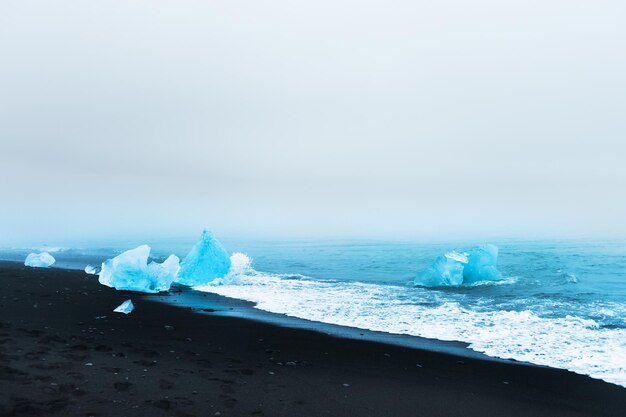 Gelo azul na praia de gelo Jokulsarlon, sul da Islândia. Bela costa do Oceano Atlântico com areia vulcânica negra