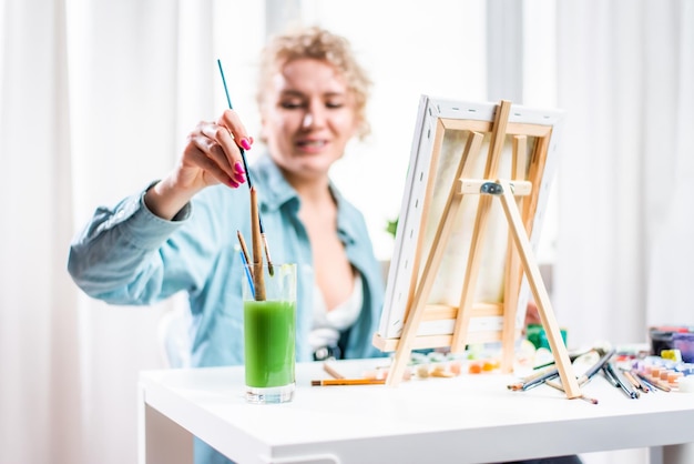 Gelockte blonde Frau, die ein Bild durch das Fenster malt