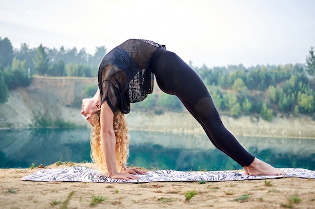 Gelockte Frau der attraktiven Rothaarigen oder vorbildliches übendes Yoga draußen