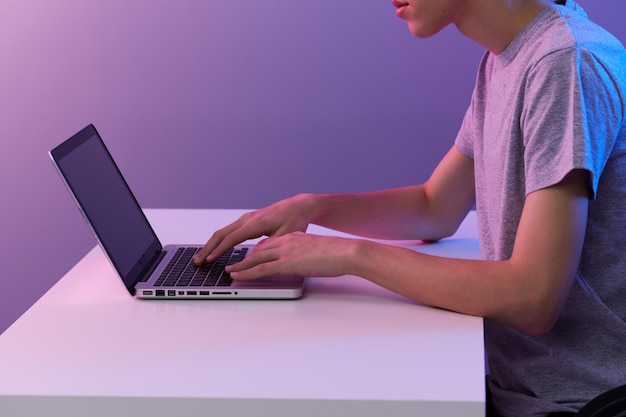 Gelockter Kerl vor violettem Hintergrund der Laptopunterhaltung