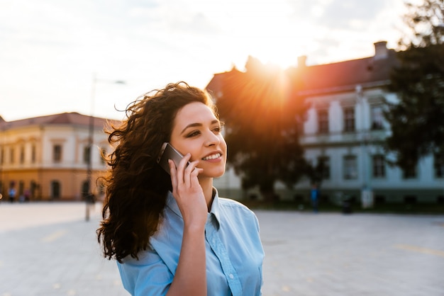 Gelocktes jugendlich unter Verwendung des Smartphone in der Stadt