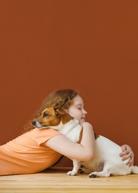 Gelocktes Mädchen, das ihren Freundhund umfasst.