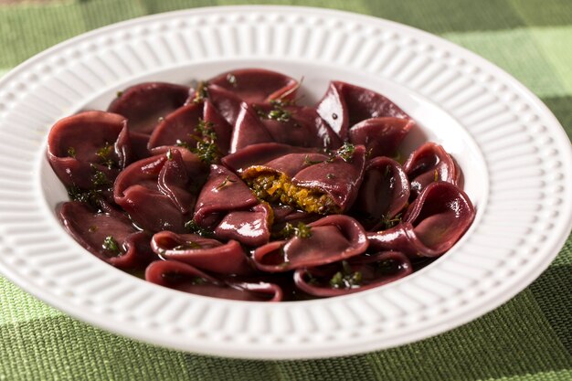 Foto gemäßigte nudeln mit rotwein und rinderhackfleisch und kürbis, serviert auf einem weißen teller über dem tisch.