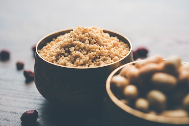 Gemahlene Erdnüsse oder Mungfali-Pulver mit ganzen und gerösteten Erdnüssen. Serviert in einer Schüssel über stimmungsvollem Hintergrund. Selektiver Fokus