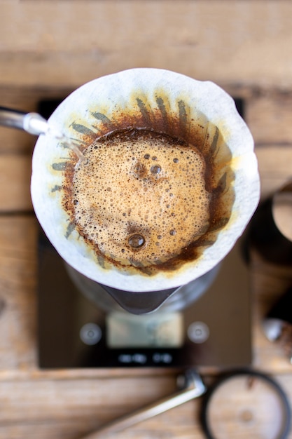 Gemahlener Kaffee im Trichter. Das Ritual der Kaffeezubereitung. Kaffeezubereitung zu Hause. Gefiltert oder überlaufen ist eine Methode, bei der Wasser auf geröstete gemahlene Kaffeebohnen gegossen wird, die in einem Filter enthalten sind