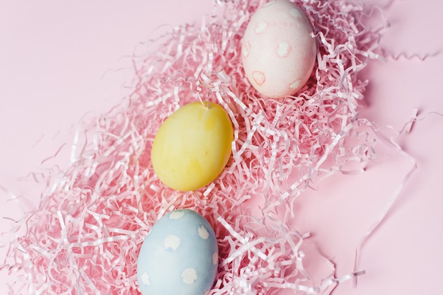 Gemalte Eier in Pastellfarben auf einem rosa Papierfüller. Moderne Osterferienschablone