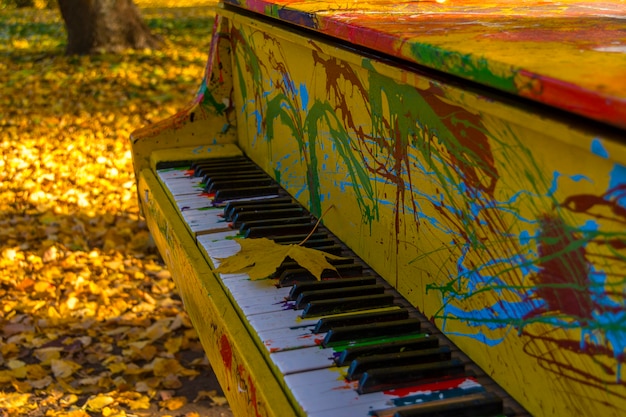 Gemalte Farben des Klaviers in einem Herbstpark. Ahornblatt liegt auf den Tasten.