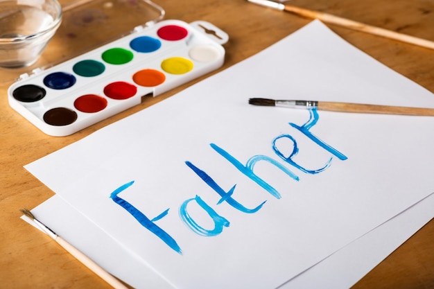 Gemaltes Wort Vater mit Wasserfarben auf weißem Papier Vatertag und Familienkonzept