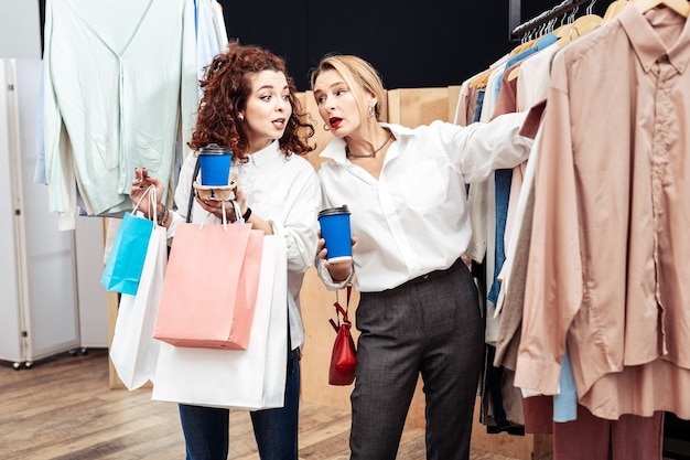 Gemeinsam einkaufen. Mutter und Tochter wählen beim gemeinsamen Einkauf stylische Bürohemden aus