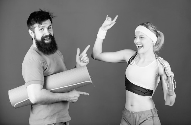 Gemeinsam stärkere Sportgeräte Sportliches Paartraining mit Fitnessmatte und Springseil Glückliche Frau bärtiger Mann trainiert im Fitnessstudio Sportlicher Erfolg Starke Muskeln und Körper stärker als je zuvor