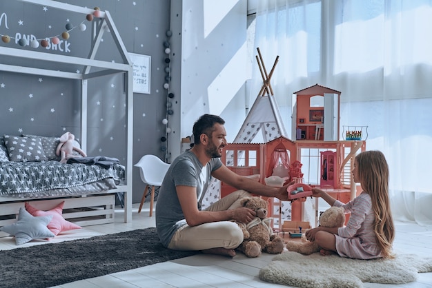 Gemeinsame Zeit genießen. Vater und Tochter spielen zusammen mit einem Puppenhaus