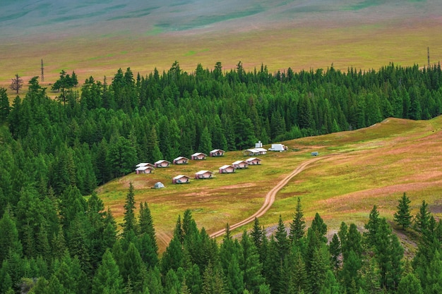 Gemeinsames Camping in der Ferne, touristischer Komplex, hölzerne Gästehäuser vor dem Hintergrund grüner Hügel. Gehöft in der Steppe. Landschaft im Hochland.