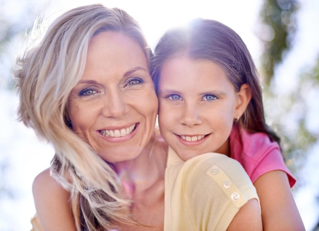 Foto gemeinsames lächeln teilen eine lächelnde mutter mit ihrer tochter auf dem rücken im freien