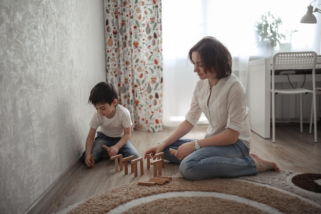 Gemeinsames Spiel von Mutter und Sohn zu Hause bauen Häuser aus einem Holz Konstruktor Konzept Kindheit