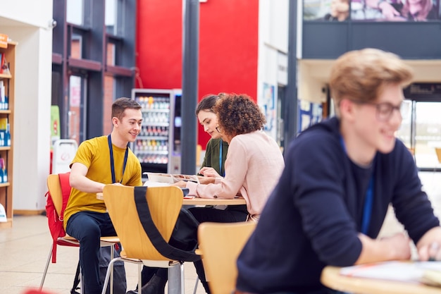 Gemeinschaftsbereich des belebten College-Campus mit Studenten, die an Tischen arbeiten