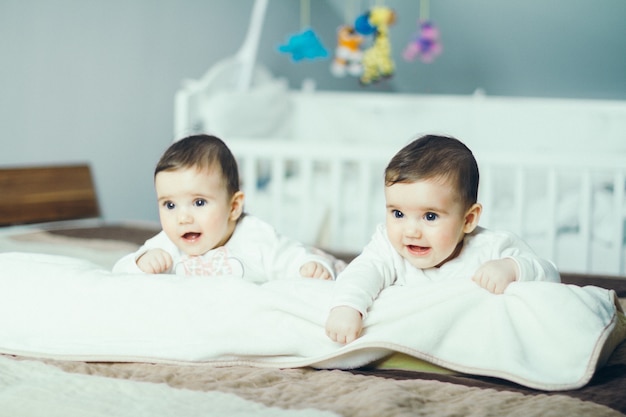 Foto gemelos bebés jugando en la cama