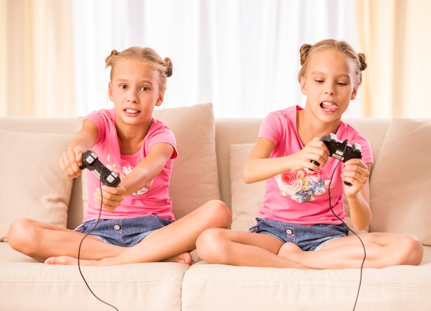 Los gemelos están jugando videojuegos con joysticks en las manos.