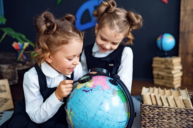 Gemelos examinando globo con lupa