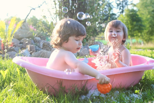 Gemelos niño y niña en el agua del baño al aire libre