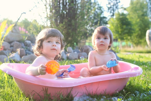 Gemelos niño y niña en agua de baño al aire libre