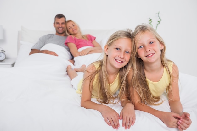 Gemelos posando en la cama frente a sus padres