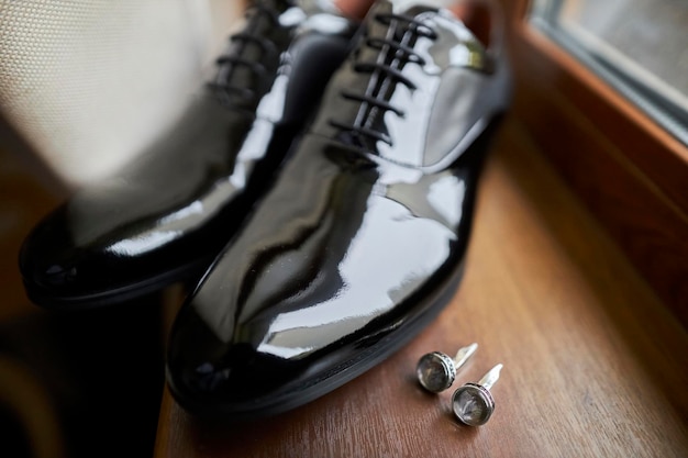 gemelos y zapatos de charol negro del novio y un reloj en la vista frontal del alféizar de la ventana