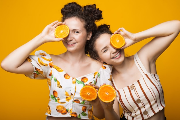 Gêmeos caucasianos cobrindo os olhos com laranjas e sorrindo