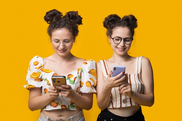 Foto gêmeos da moda com cabelos cacheados e óculos conversando no celular