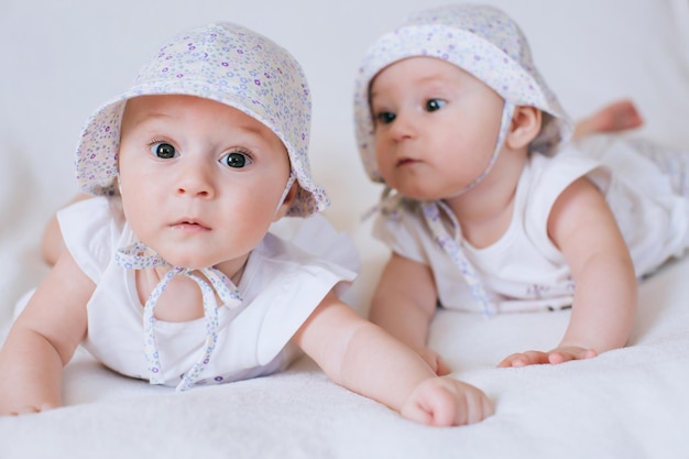 Gêmeos de crianças felizes em chapéus engraçados em um fundo branco