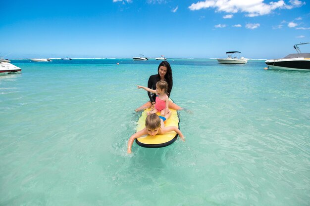 Gêmeos, menino e menina, com a mãe surfando no oceano em um quadro-negro