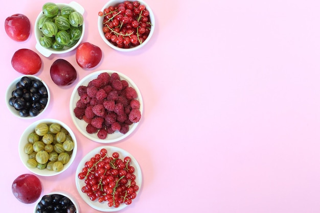 Gemischte Beeren in Betonplatte auf rosa Hintergrund mit leerem Teller und Kopierraum