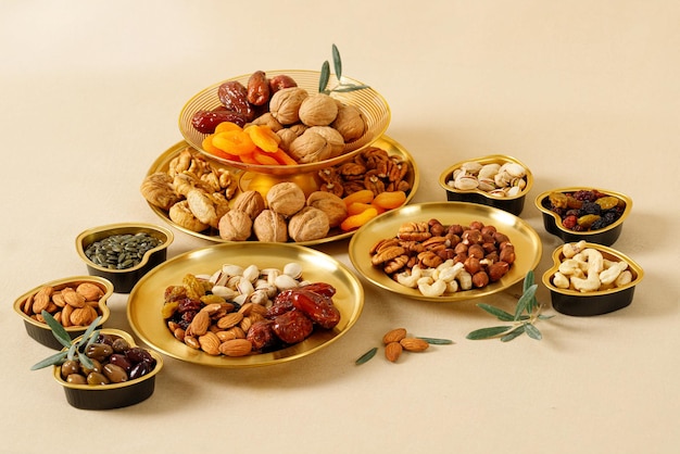 Gemischte Nüsse und Trockenfrüchte auf einem goldenen Teller. Symbole des jüdischen Feiertags Tu Bishvat. Gesunde Snackmischung aus Bio-Nüssen und Trockenfrüchten
