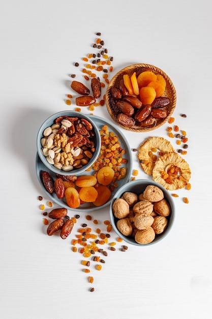 Gemischte Nüsse und Trockenfrüchte auf einem Teller auf einem weißen Holztisch mit Kopierraum. Symbole des jüdischen Feiertags Tu Bishvat Gesunder Snack - Mischung aus Bio-Nüssen und Trockenfrüchten.