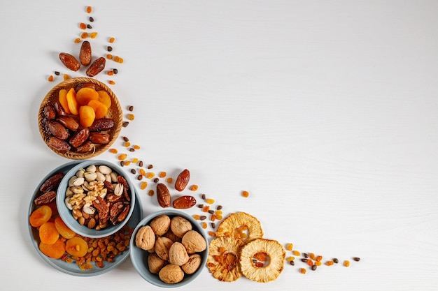 Gemischte Nüsse und Trockenfrüchte auf einem Teller auf einem weißen Holztisch mit Kopierraum. Symbole des jüdischen Feiertags Tu Bishvat Gesunder Snack - Mischung aus Bio-Nüssen und Trockenfrüchten.