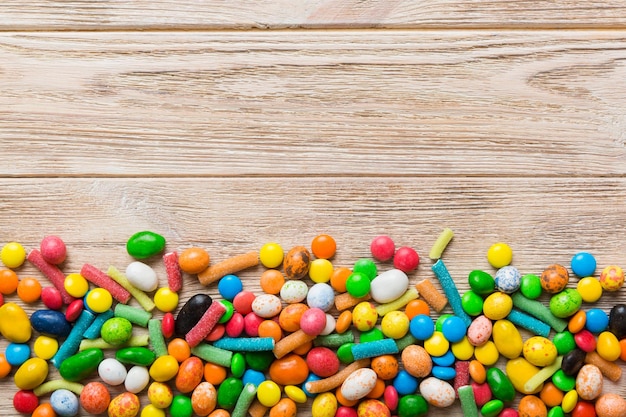 Gemischte Sammlung bunter Süßigkeiten auf farbigem Hintergrund. Flacher Draufsichtrahmen aus bunten, mit Schokolade überzogenen Süßigkeiten