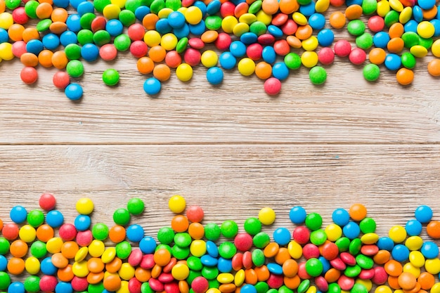 Gemischte Sammlung bunter Süßigkeiten auf farbigem Hintergrund. Flacher Draufsichtrahmen aus bunten, mit Schokolade überzogenen Süßigkeiten