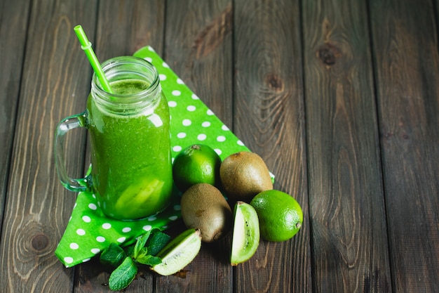 Gemischter grüner Smoothie mit Bestandteilen auf Holztisch