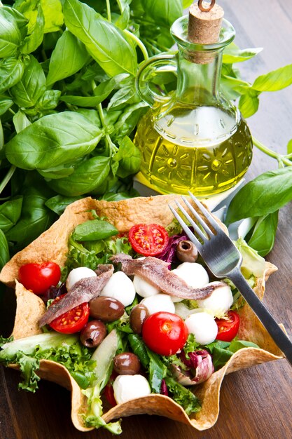 Foto gemischter salat mit mozzarella und sardellen in einem brotkorb