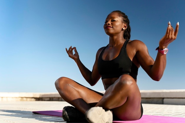 Gemischtrassige Frau, die Yoga-Asanas am Strand mit geschlossenen Augen macht