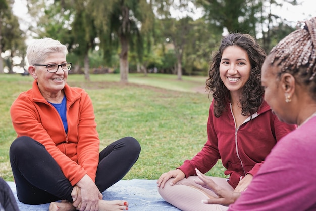 Gemischtrassige Frauen, die im Stadtpark im Freien sitzen und reden - Generationenübergreifende Menschen, die zusammen Spaß haben