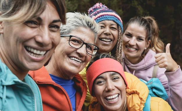 Gemischtrassige Frauen, die Spaß haben, ein Selfie im Wald zu machen, während sie einen Trekkingtag machen - Generationenübergreifende Menschen genießen den Tag in der Natur