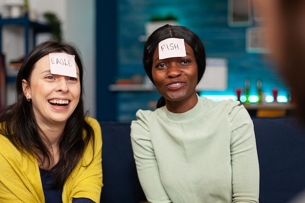 Gemischtrassige Freunde, die Freundschaft beim Spielen genießen Gemischte Rassen, die Spaß haben, zusammen lachen, während sie spät in der Nacht auf dem Sofa sitzen.