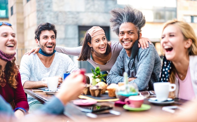 Gemischtrassige Freunde, die Spaß beim gemeinsamen Trinken im Kaffeehaus haben