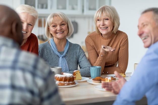 Foto gemischtrassige gruppe positiver älterer menschen, die tee mit kuchen trinken