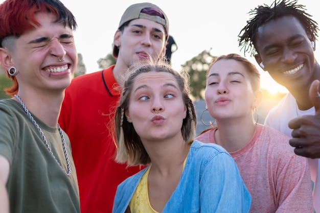 Gemischtrassige Gruppe von Freunden, die ein Selfie machen und das Gesicht verziehen Junge mileniale Menschen, die sich draußen amüsieren