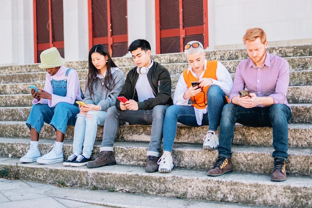 Gemischtrassige Gruppe von Freunden, die mit ihren Mobiltelefonen im Freien surfen