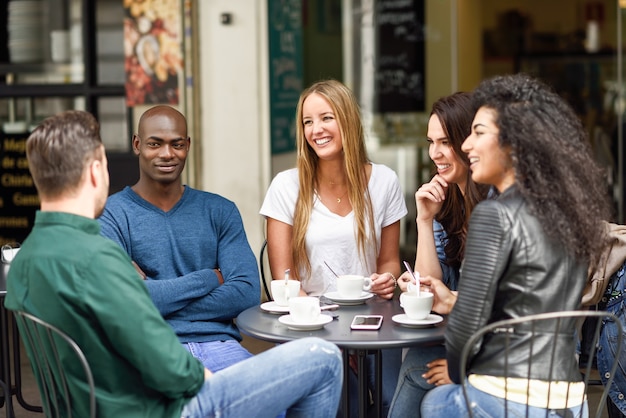 Gemischtrassige Gruppe von fünf Freunden, die zusammen einen Kaffee trinken