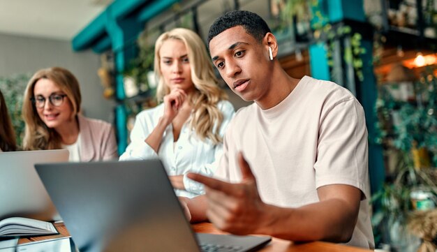 Gemischtrassige kreative Leute im modernen Büro. Gruppe junger Geschäftsleute und Seniorchef arbeiten mit Laptop, Tablet, Smartphone, Notebook, Grafiken zusammen. Erfolgreiches Team im Coworking