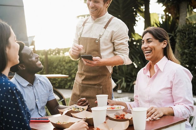 Gemischtrassige Leute, die im Imbisswagen-Restaurant im Freien essen - Fokus auf reifem Frauengesicht